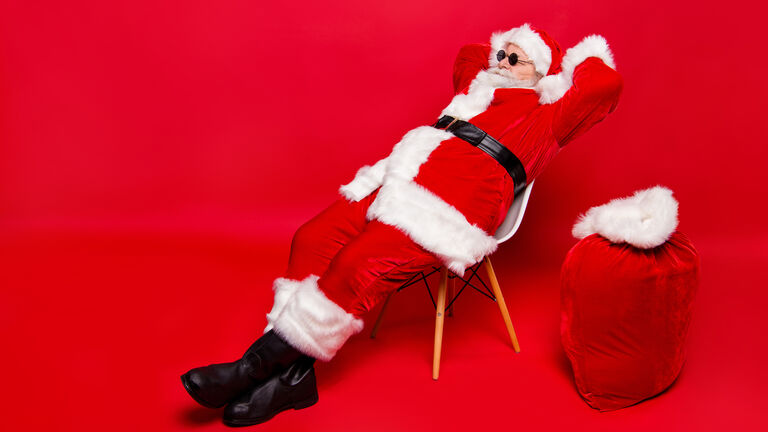 Ein Weihnachtsmann mit Geschenkesack, der sich auf einem Stuhl ausruht