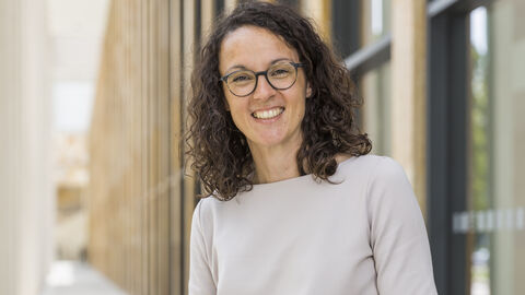 Angela Dorn, Hessische Ministerin für Wissenschaft und Kunst Ministerin Angela Dorn steht vor einem Hochschulgebäude, sie lächelt und trägt ein weißes Kleid