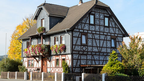 Haus mit Kratzputz-Giebelseite in Cölbe bei Marburg Ein Haus im Kratzputz-Stil von außen; im Gefache des Fachwerkhauses sind Bilder eingefügt