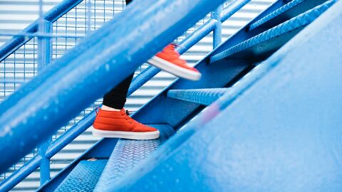 Schritt für Schritt geht's voran Füße in roten Turnschuhen steigen eine Treppe hinauf