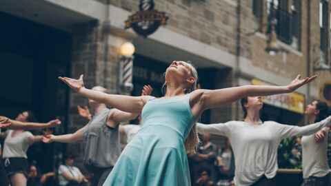 Tänzerinnen und Tänzer auf der Straße Tänzerinnen und Tänzer stehen mit weit geöffneten Armen auf der Straße, den Blick RIchtung Himmel