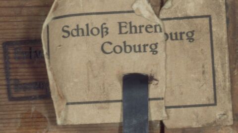 474 ist die Inventarnummer nach dem Inventar der Gemälde der Ehrenburg. Das Inventar wurde in den zwanziger Jahren des 20. Jahrhunderts angefertigt. Der dahinter liegende Brennstempel kennzeichnet das Gemälde vermutlich als Privatbesitz des Herzogs von Sachsen-Coburg-Gotha. Nahaufnahme eines Klebezettels, auf dem "Schloss Ehrenburg Coburg" steht