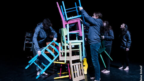 Jugendliche bauen aus leuchtenden Stühlen einen Turm