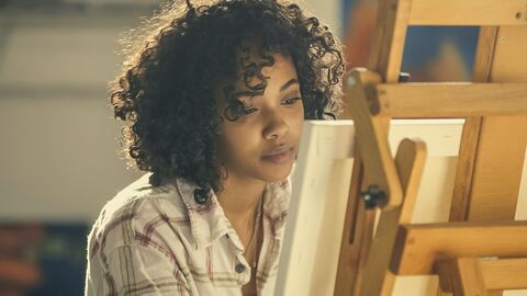 Verschiedene Arbeitsstipendien stehen bereit Eine Frau sitzt vor einer Leinwand und malt