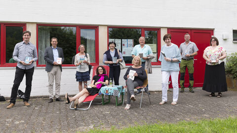 Ministerin Dorn liegt in einem Liegestuhl, umgeben von den Mitarbeiter*innen der Bücherei