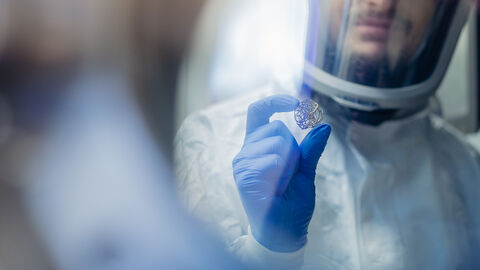 Hessen will die besten Köpfe ins Land holen Ein Forscher im Schutzanzug, der einem anderen Forscher ein Zeichen gibt