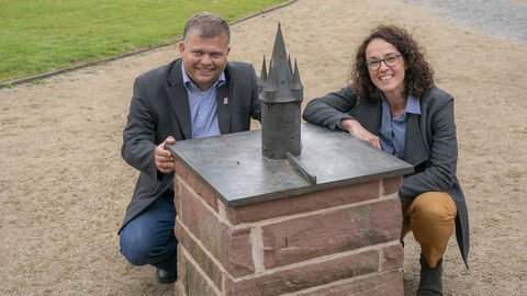 Ministerin Dorn und der Bürgermeister von Neustadt, Thomas Groll, knien neben einem Modell des Turms