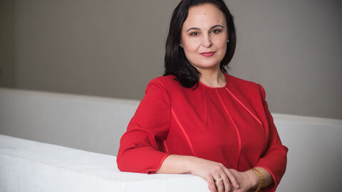 Ayse Asar im roten Kleid, den Arm auf eine weiße Brüstung gestützt