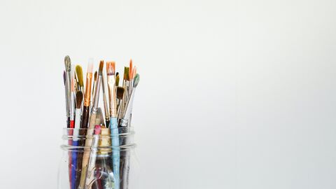 Ein Glas mit Pinseln vor grauem Hintergrund