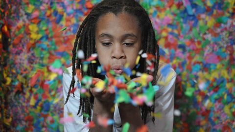 Ein Kind pustet Konfetti in die Kamera