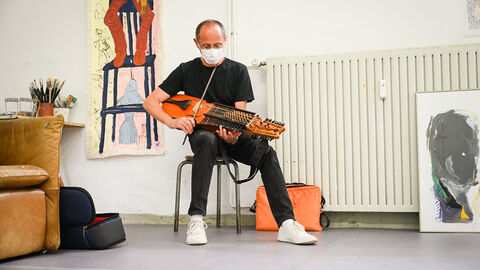 Marco Ambrosini aus Hatzfeld an der Eder spielt die Nyckelharpa (oder „Schlüsselfidel“) Ein Mann sitzt auf einem Stuhl und spielt ein Instrument, das aussieht wie eine Mischung aus Geige und Zither. Er spielt es mit einem Bogen