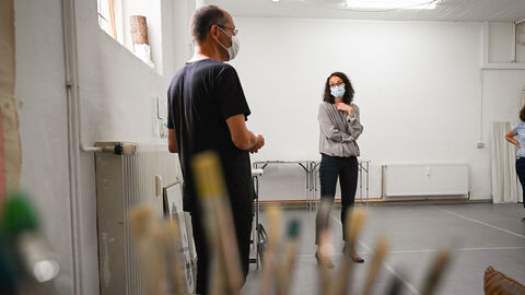 Das Atelier in Wiesbaden teilen sich mehrere Künstlerinnen und Künstler Ministerin Dorn steht mit einem Künstler in seinem Atelier