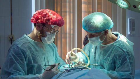 Der Arztberuf gehört zu den reglementierten Berufen Zwei Mediziner im OP-Saal, sie beugen sich über einen Patienten