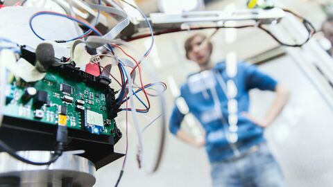 Laboranlage, im Hintergrund steht verschwommen ein Student