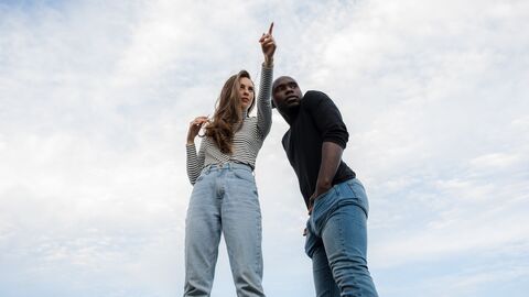 Eine Frau zeigt in eine Richtung, ein Mann steht neben ihr und schaut in dieselbe Richtung