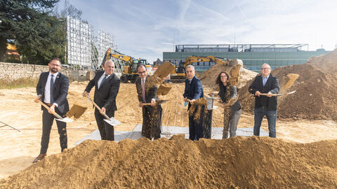 Ministerin Angela Dorn und weitere Vertreter des Landes und der Hochschule stehen nebeneinander vor einem Haufen Sand und schwingen Spaten 