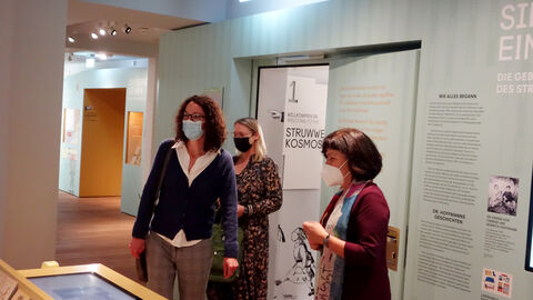 Kunst- und Kulturministerin Angela Dorn (links) hat heute dem Struwwelpeter-Museum in Frankfurt die Auszeichnung „Museum des Monats“ verliehen und Leiterin Beate Zekorn-von Bebenburg (r) 1.000 Euro Preisgeld überreicht. Ministerin Dorn steht mit der Museumsleiterin im Empfangsbereich des Museums vor einem Touchsceen