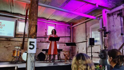 Ministerin Dorn steht auf einer pink erleuchteten Bühne und hält eine Rede