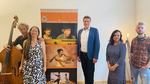 Staatssekretärin Asar steht mit Kulturschaffenden vor einem Aufsteller