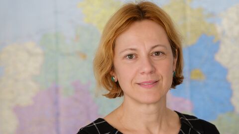 Prof. Dr. Sabine Mecking steht vor einer Weltkarte