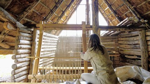 Die "Zeiteninsel" lässt elf Jahrtausende Landschafts- und Kulturgeschichte lebendig werden. Eine Frau sitzt in einer nachgebauten antiken Behausung aus Holz und webt