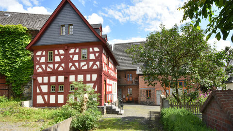 Eines der preisgekrönten Objekte des Hessischen Denkmalschutzpreises 2021: Ein rot gehaltenes Fachwerkhaus mit Garten und angrenzender Scheune