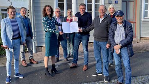 Ministerin Dorn steht mit mehreren Vertreter*innen der Stadt Wanfried vor dem ausgezeichneten Haus und überreicht die Urkunde