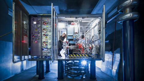 Eine Forscherin steht in einer verkabelten Anlage