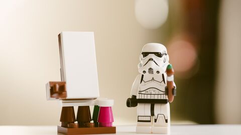Ran an die Pinsel! Kleine Star-Wars-Figur steht mit einem Pinsel in der Hand neben einer Leinwand