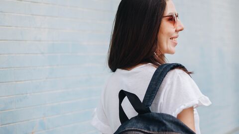 Hessens International Summer Universities finden in Coronazeiten online statt Eine Frau mit Rucksack und Sonnenbrille blickt lächelnd zur Seite