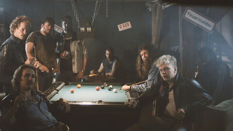 Szene aus dem Film "Coup" Szene aus dem Film "Coup": Männer stehen in einem dunklen Raum um einen Billardtisch herum