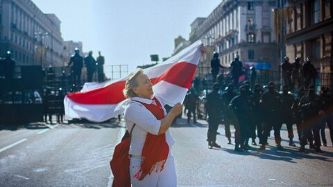 Szene aus dem Film "Courage": Eine Frau schwenkt eine Fahne bei einer Demonstration