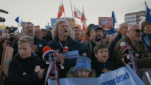 Szene aus "Die Kafka-Konferenz": eine protestierende Menschenmenge mit Fahnen