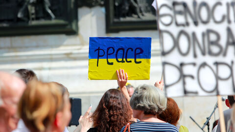 Hessen und seine Hochschulen unterstützen Studierende und Forschende aus der Ukraine  Eine Person hält bei einer Demonstration ein Schild in den ukrainischen Farben hoch, auf dem "Peace" ("Frieden") steht