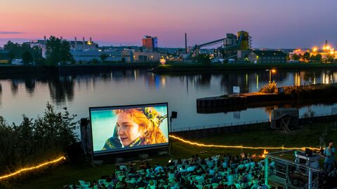 Open-Air-Festivals wie dieses am Offenbacher Hafen 2 bereichern Hessens Kulturlandschaft Blick auf den Offenbacher Hafen, davor ist eine Leinwand aufgebaut, auf der ein Film abgespielt wird; das Publikum sitzt davor