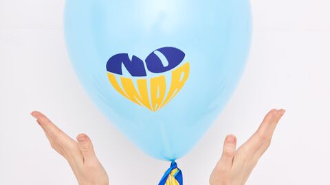 Zwei Hände halten einen Luftballon, auf dem "no war" (kein Krieg) in den ukrainischen Farben steht
