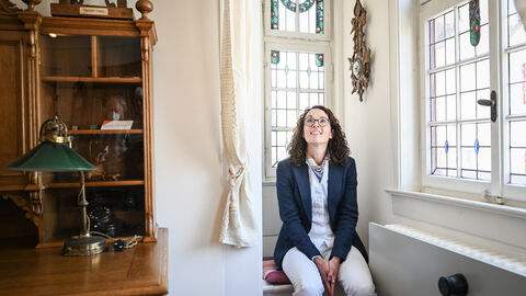 Ministerin Dorn sitzt auf einer Fensterbank im Vogelsberger Heimatmuseum und bestaunt die Einrichtung