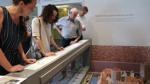 In der Ruine der ehemaligen Reichsburg Hayn hat der Geschichts- und Heimatverein Dreieichenhain eine moderne Ausstellung eingerichtet. Ministerin Angela Dorn schaut sich mit Vertreterinnen und Vertretern des Museums Dreieich eine Miniatur der Stadt an