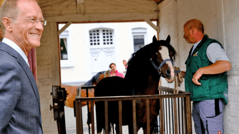 Mehr als zwei Jahre lang haben engagierte Dorfbewohnerinnen und -bewohner das „Wiegehäuschen“ in Eigenleistung restauriert Staatsminister Axel Wintermeyer steht im Wiegehäuschen, im Hintergrund führt ein Mann ein Pferd auf die Wiegefläche