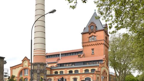 Der Alte Schlachthof in Gießen: Ein Backstein-Industriebau mit grauem spitzen Dach und einem großen Schornstein