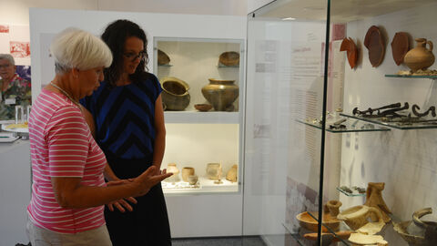 Einen Schwerpunkt des Heimatmuseums Schwanheim bilden die archäologischen Fundstücke.  Ministerin Dorn schaut sich eine Vitrine mit archäologischen Fundstücken an.