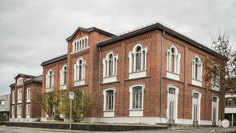 Die Freiherr-von-Schütz-Schule Bad Camberg von außen: Ein wuchtiges Schulgebäude in helbbraunem Backstein mit weißen Fenstern