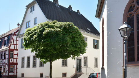 Das ehemalige Pfarrhaus in Nidderau von außen: Ein zweistöckiges Gebäude mit weißer Fassade und grauem Dach