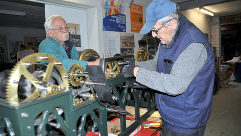 Henning Hehner und Bruno Schmück stehen am Uhrwerk und basteln daran herum