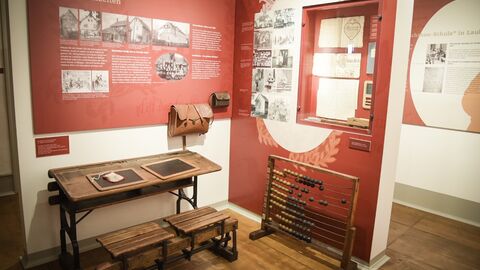 Blick in eine Museumsecke mit einer alten Schulbank und Details aus einem historischen Klassenzimmer