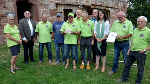 Ministerin Dorn mit den Mitgliedern des Heimatvereins Aue, die neongalbe Shirts tragen, vor der Wasserburg