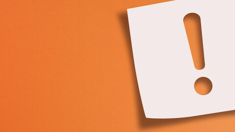 Ein Zettel mit einem Ausrufezeichen auf orangefarbenem Grund
