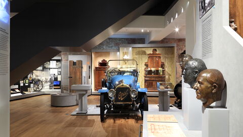 Blick in die Dauerausstellung des Stadt- und Industriemuseums Rüsselsheim Blick in die Dauerausstellung des Stadt- und Industriemuseums Rüsselsheim: Man sieht einen Oldtimer und Bronzebüsten