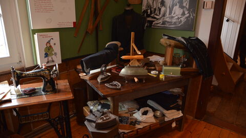 Bild 5 von 5 Nähmaschine und Bügeleisen - ganz klar der Arbeitsplatz eines Schneiders oder einer Schneiderin.. Eine Schneiderwerkstatt im Seulberger Heimatmuseum mit Gegenstänen des Handwerks; zum Beispiel ein antikes Bügeleisen und eine Nähmaschine