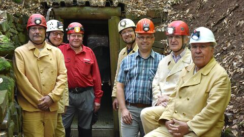 Mitglieder des Vereins Altbergbau Bergstraße-Odenwald stehen vor einem Minenschacht, sie tragen Grubenhelme